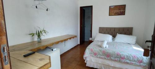 a bedroom with a bed and a wooden table at Pousada e Restaurante Dona Siroba in Morretes