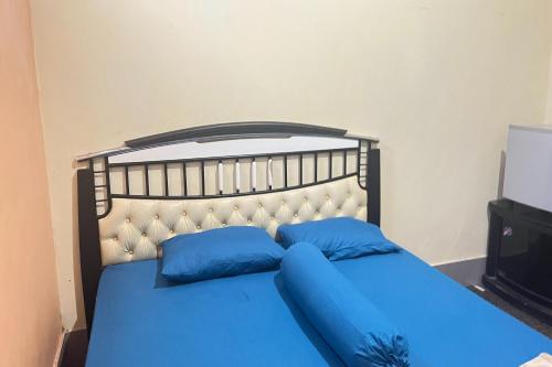 uma cama azul com almofadas azuis num quarto em OYO 93416 Wisma Alam Syariah em Mamuju