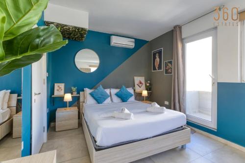 a bedroom with a large bed with blue walls at Modern Paceville Suites with WIFI & AC by 360 Estates in Paceville
