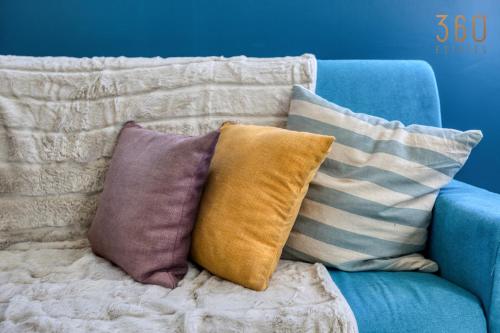 a pile of pillows sitting on a blue couch at Modern Paceville Suites with WIFI & AC by 360 Estates in Paceville