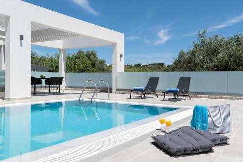 a swimming pool with chairs and a table in a house at Armonia Suites in Gennadi