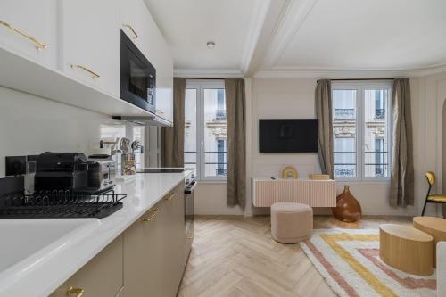 une cuisine avec des comptoirs blancs et un salon dans l'établissement Poetic Stay - Opera, à Paris