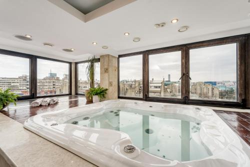a large bath tub in a room with windows at Apartment Botero in Belgrade