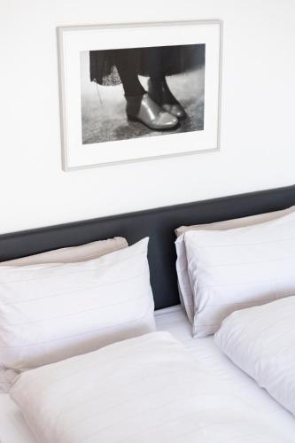 two beds with white pillows and a picture above them at Cësa Marmolada 1318 in Ortisei