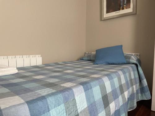 Una cama con una almohada azul encima. en Habitación Aeropuerto Loiu, en Loiu