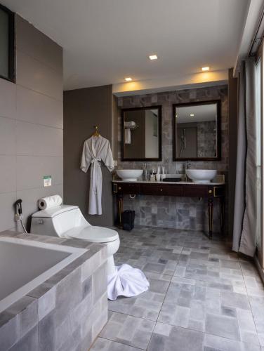 a bathroom with two sinks and a tub and a toilet at Le Thatluang D'oR Boutique Hotel in Vientiane