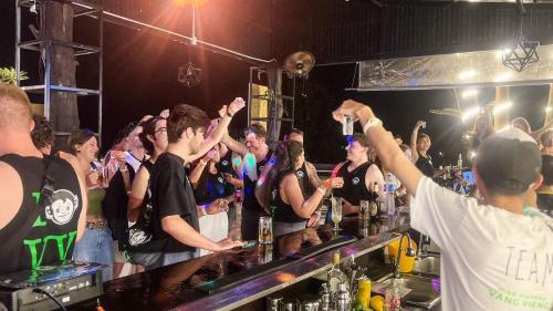 a group of people standing behind a bar with their arms up at Mad Monkey Vang Vieng in Vang Vieng