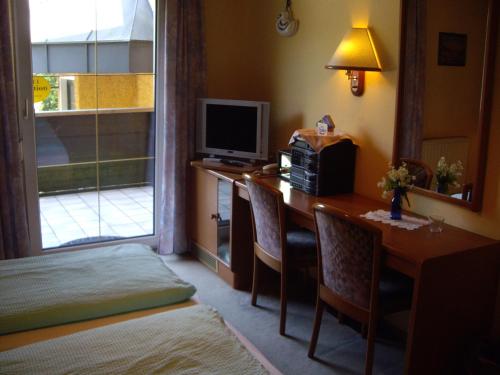 a room with a desk with a computer and a television at Hotel Pension Stadlhuber Aktivpark Kremsmünster in Kremsmünster