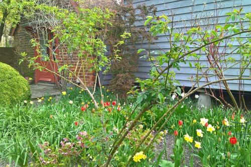 a garden with flowers in front of a house at The Granary at Palm Tree House in S.E. Kent in Lyminge