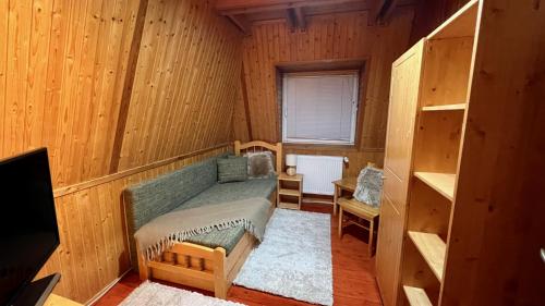 een kamer met een groene bank in een houten kamer bij Naposdomb Vendégház in Miskolc