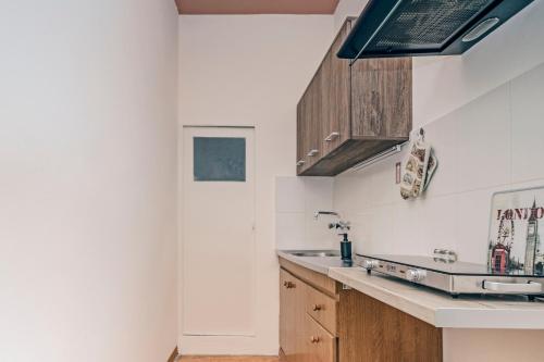 a kitchen with white walls and wooden cabinets at Venetian Reale Apartment in Corfu Town