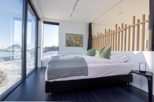 a bedroom with a large bed and large windows at The Oceanfront Private northern lights villa. in Reynivellir