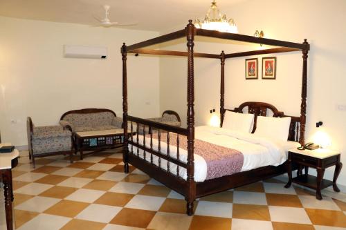 a bedroom with a canopy bed and two chairs at Hotel Fort Padmawati in Pratāpgarh