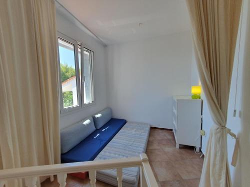 a living room with a blue couch and a window at Sea Satin Anavyssos in Anavissos