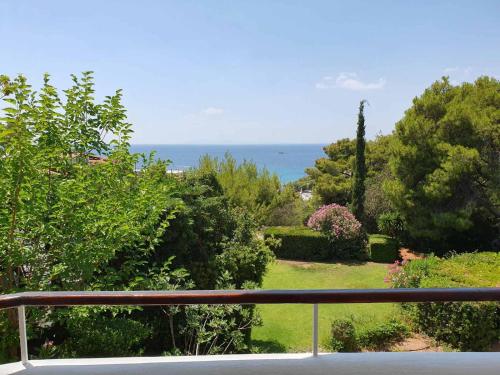a balcony with a view of a garden and the ocean at Sea Satin Anavyssos in Anavissos