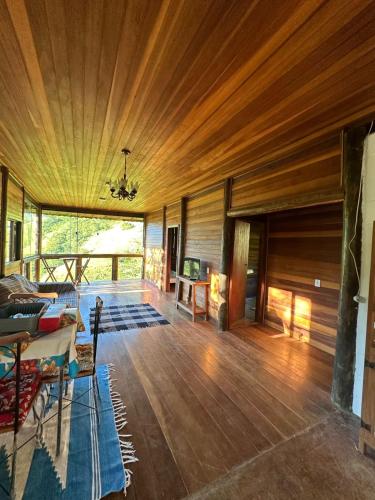 Paraíso da serra في ساو فرنسيسكو كزافييه: غرفة معيشة وأرضيات خشبية وسقف خشبي