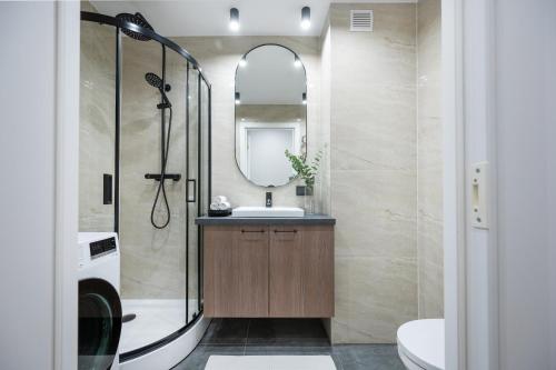 een badkamer met een douche, een wastafel en een spiegel bij Apartments near Akropolis shopping center. in Vilnius