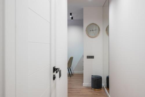 a hallway with white doors and a clock on a wall at Apartments near Akropolis shopping center. in Vilnius