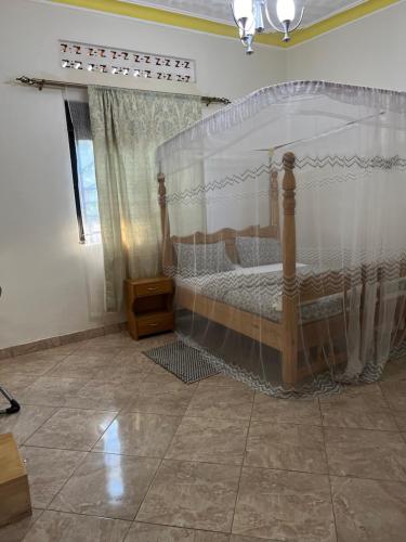 1 dormitorio con 1 cama con dosel en Tropical Oasis Retreat, en Kisubi