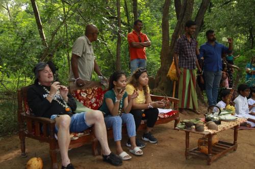 a group of people sitting on benches in a forest at Tuktukraju Home stay 