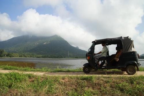 two people in a golf cart parked next to a body of water at Tuktukraju Home stay 