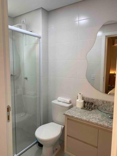 a bathroom with a toilet and a glass shower at Kitnet alto padrão sem taxa de limpeza in Cachoeira do Sul
