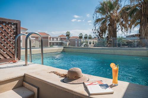 a hat and a book next to a swimming pool at Caldera Creta Paradise in Plataniás