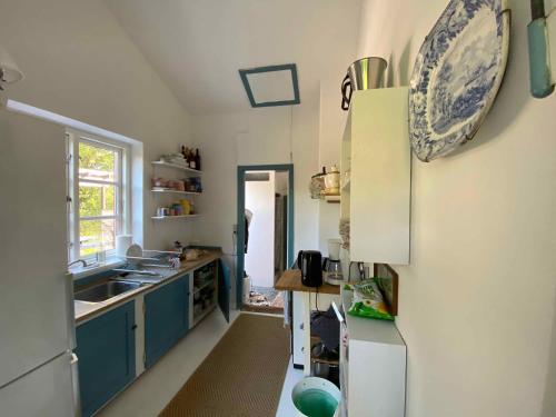 una cocina con armarios azules y una placa en la pared en Charming Thatched-roof Cottage From 1947, en Dronningmølle