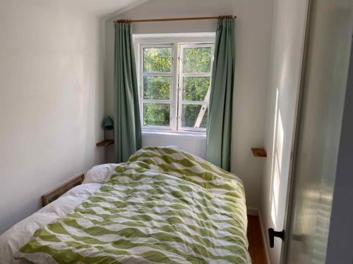 1 cama en un dormitorio con ventana en Charming Thatched-roof Cottage From 1947, en Dronningmølle