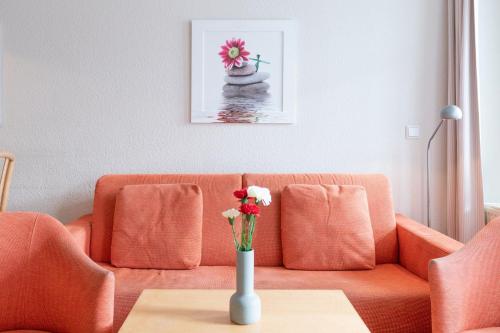 een woonkamer met een bank en een vaas met bloemen op een tafel bij Fewo 350, Seepark Sellin in Ostseebad Sellin