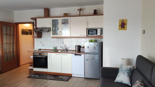 una cucina con armadi bianchi e frigorifero in acciaio inossidabile di Apartments Tomišić a Capodistria