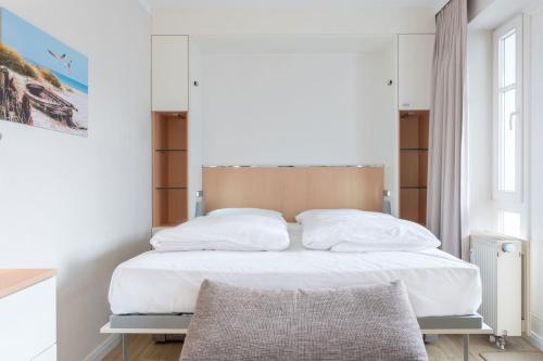 - une chambre avec un lit doté de draps et d'oreillers blancs dans l'établissement Seepark Sellin FeWo AG Whg 376, à Sellin