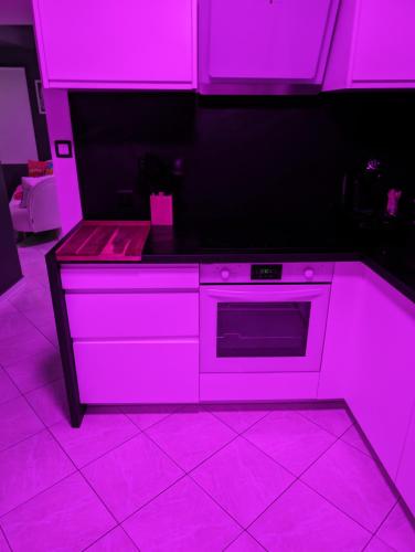 - une cuisine avec des lumières roses au-dessus d'une cuisinière dans l'établissement Le Spacidulé, à Saint-Amand-les-Eaux