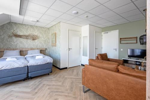 um quarto com uma cama, um sofá e uma televisão em Strandplevier Suites em De Koog