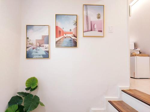 vier foto's op een muur in een hal met een plant bij Daol Stay in Seoul