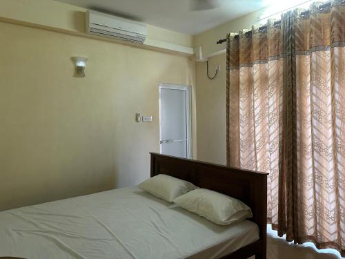 a bedroom with a bed and a window with curtains at Nexus 25 in Colombo