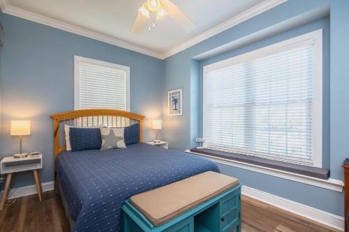 a blue bedroom with a bed and two windows at Retreat 5B - Edisto Blessing in Edisto Island