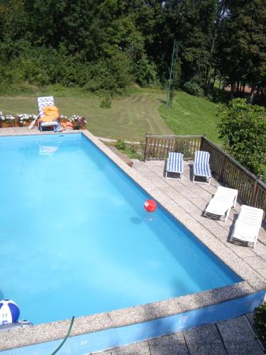 a swimming pool with two lounge chairs and a red ball at Hotel Pension Stadlhuber Aktivpark Kremsmünster in Kremsmünster