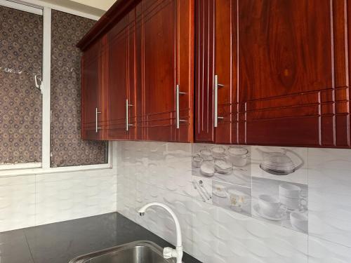uma cozinha com armários de madeira e um lavatório em Nexus 25 em Colombo