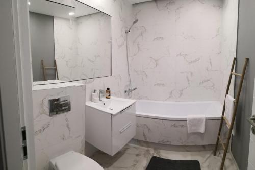 baño blanco con bañera, lavabo y aseo en Indigo Apartment Urusagului, en Floreşti