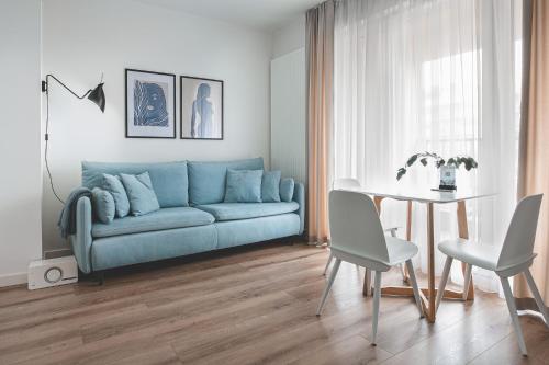 a living room with a blue couch and a table at Tuyo Apartments Bokserska in Warsaw