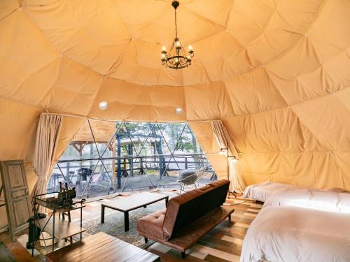 a room with a tent with a couch and a table at Nagano GLAMPINGBASE enCamp in Shiojiri