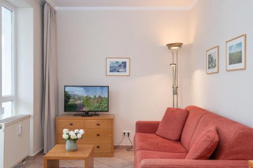 ein Wohnzimmer mit einem roten Sofa und einem TV in der Unterkunft Fewo 641, Seepark Sellin in Ostseebad Sellin