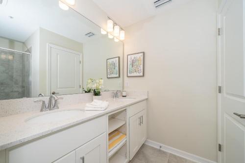 een witte badkamer met een wastafel en een spiegel bij 3120-206DR STOREY LAKE, CONDO 2/2 GARDEN VIEW in Kissimmee