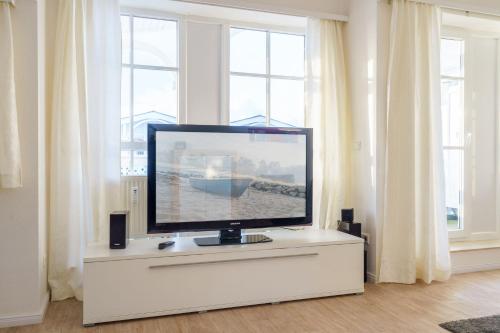 einen Flachbild-TV auf einer Kommode in einem Zimmer mit Fenstern in der Unterkunft Seepark Sellin FeWo AG Whg 705 in Ostseebad Sellin