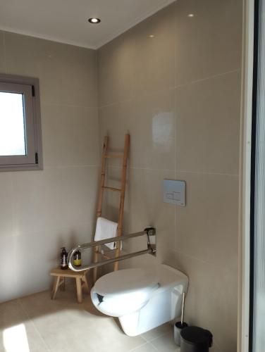 a bathroom with a toilet and a chair in it at Pnoe Eco Residences in Amaliás