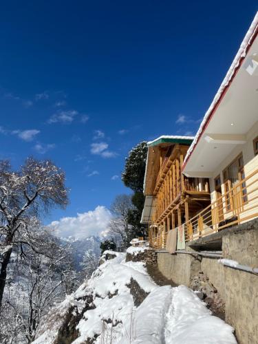 un chemin enneigé à côté d'un bâtiment dans l'établissement Flüstern Homestay, à Nagar