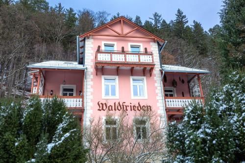 a pink house with a sign on the side of it at Bio-Hotel Villa Waldfrieden in Bad Schandau