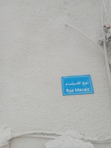 un cartello blu sul lato di un muro bianco di Mosaic House 24 a Raoued