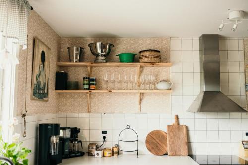 a kitchen with white tiled walls and wooden shelves at Skrea Backe Bo in Falkenberg
